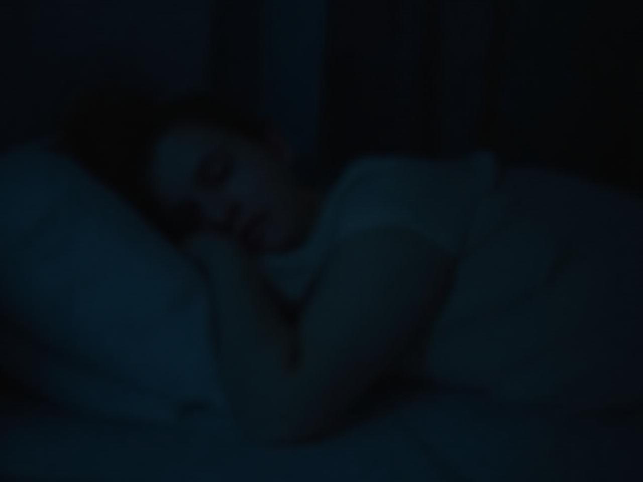 A serene image of a person sleeping peacefully in a dark and comfortable bedroom. Soft lighting creates a calming atmosphere. Keywords: restful sleep, deep sleep, peaceful night, bedroom tranquility, improving sleep quality.